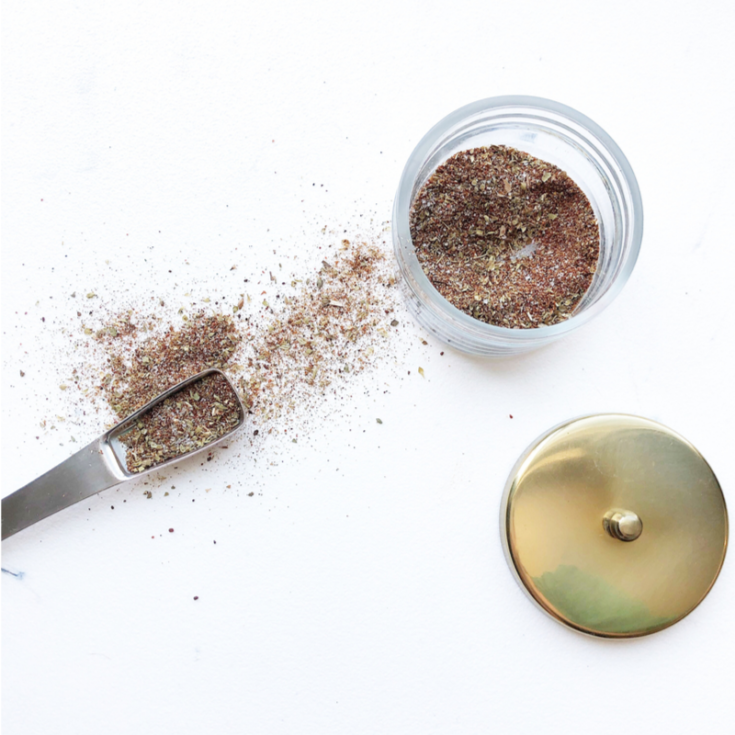 Taco seasoning in a glass jar on a white background