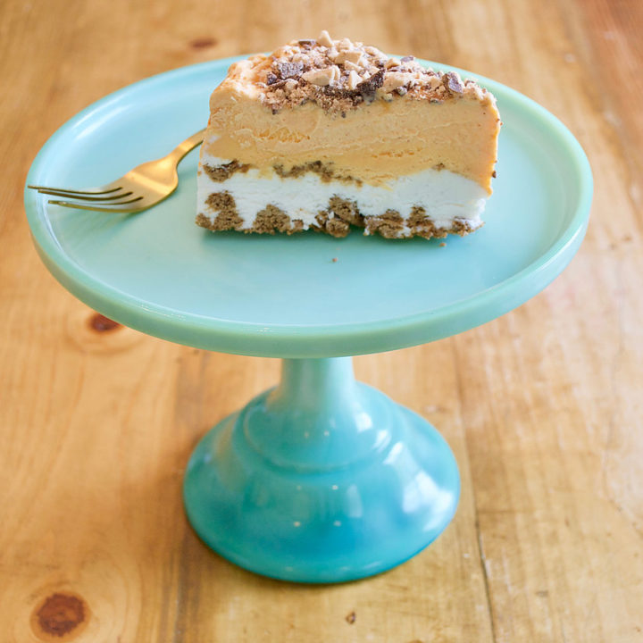 pumpkin gingersnap ice cream cake on a teal cake stand with a fork.