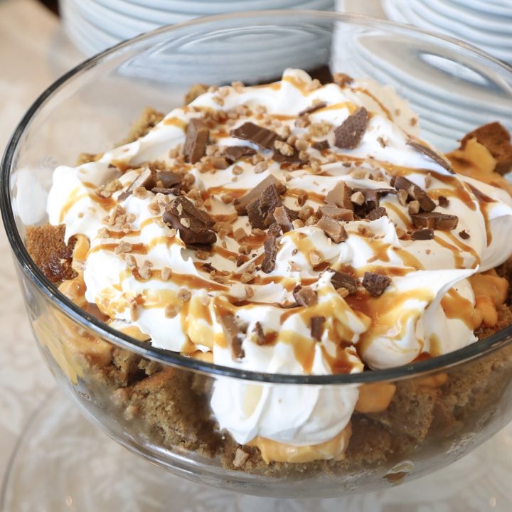 layers of spice cake, pumpkin pudding, caramel sauce and heath bars in a trifle dish on a table