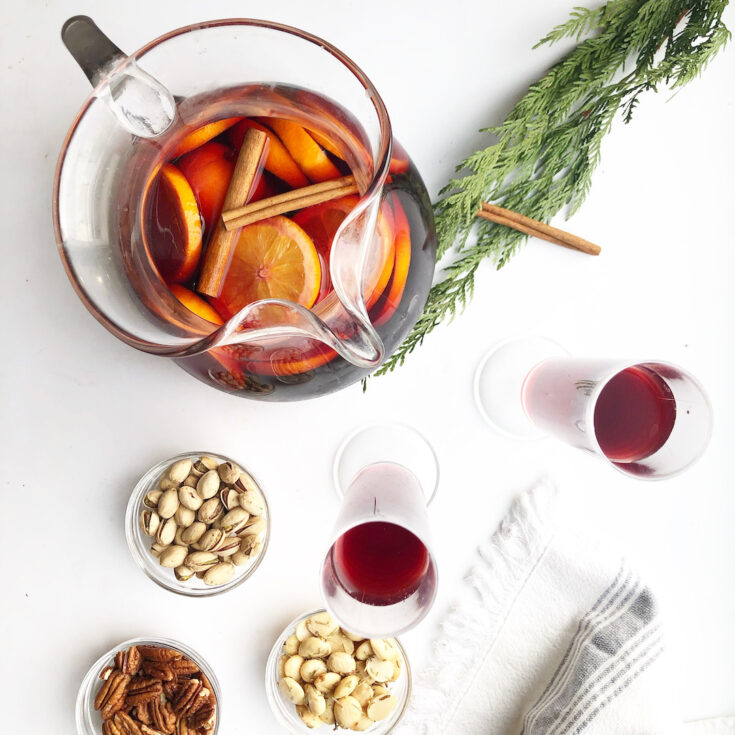 cranberry spritzer in pitcher with nuts in bowls