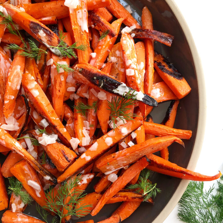 roasted carrots on a grey platter with fresh dill garnish