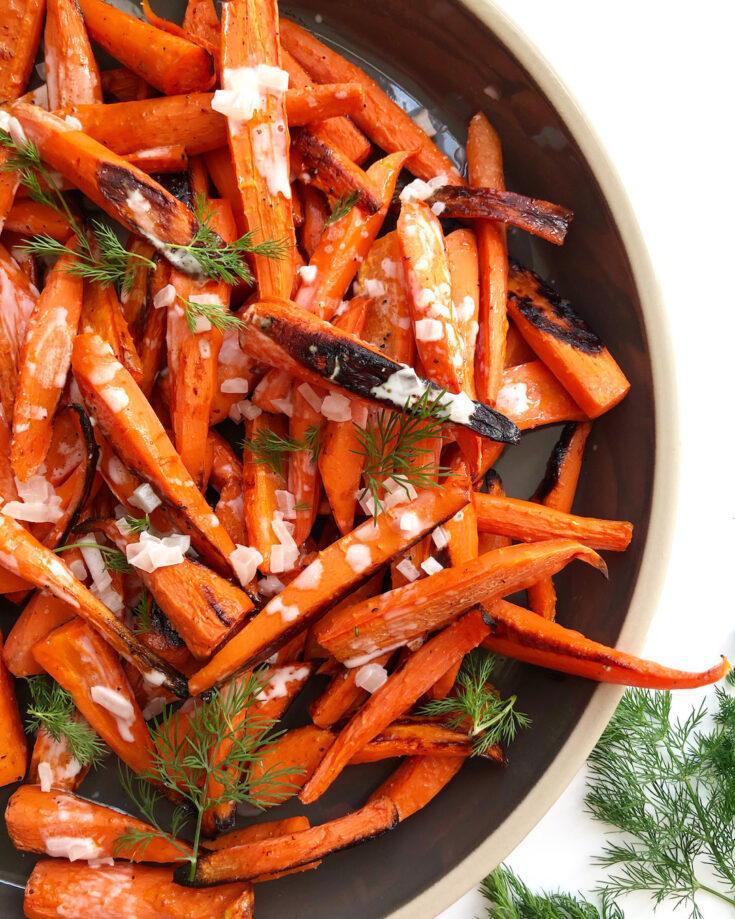 roasted carrots on a grey platter with fresh dill garnish