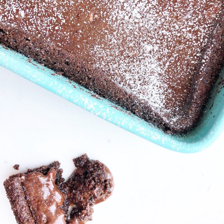 gluten free brownies in a teal baking dish topped with powdered sugar