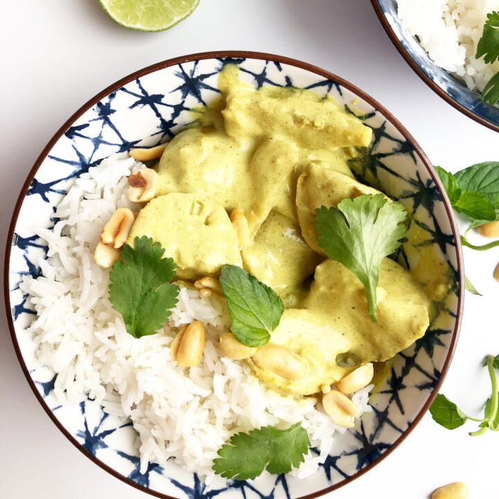 yellow curry with chicken and potatoes in a blue bowl with cilantro and peanuts on top