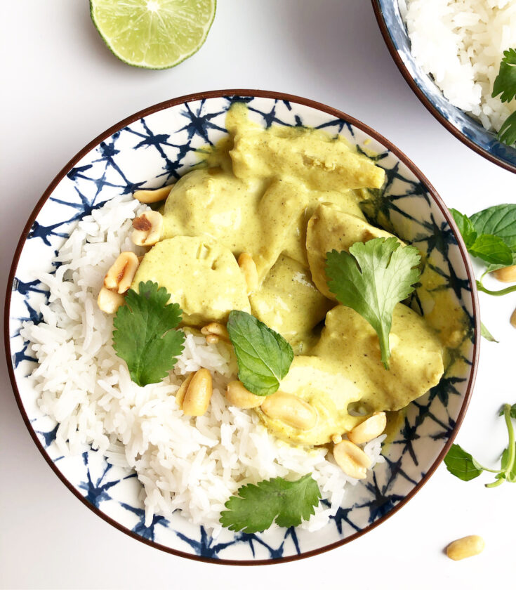 yellow curry with chicken and potatoes in a blue bowl with cilantro and peanuts on top