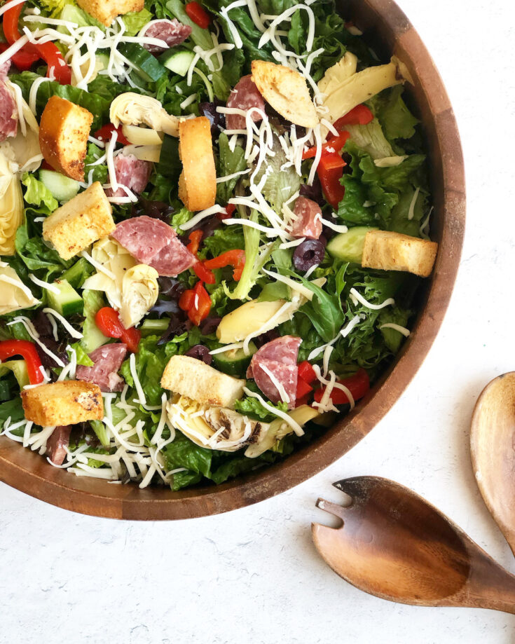 Antipasto salad in wood bowl with wooden salad spoons