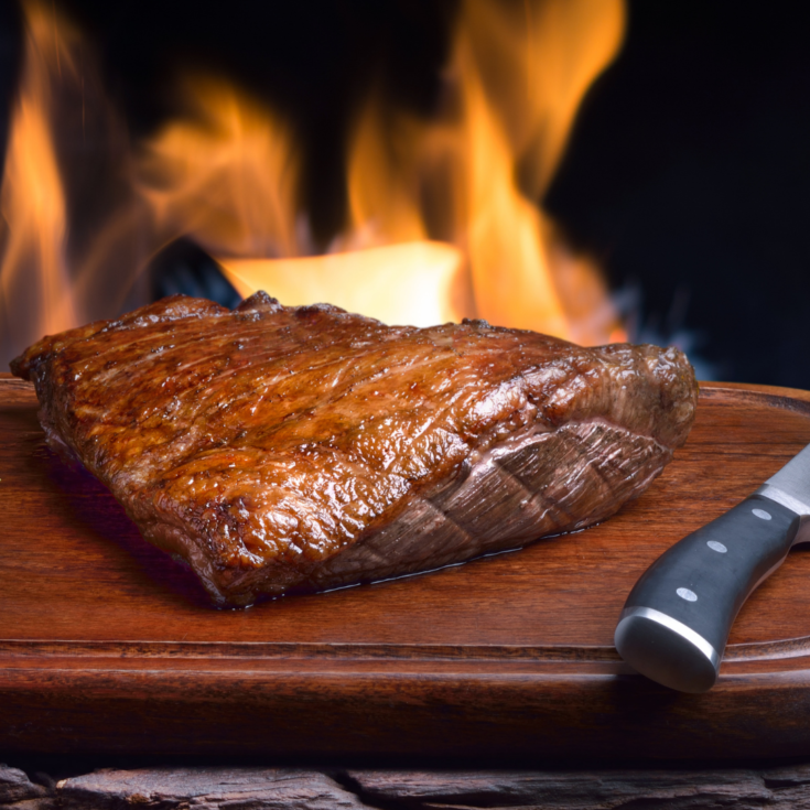 Churrasco meat on a cutting board next to a knife