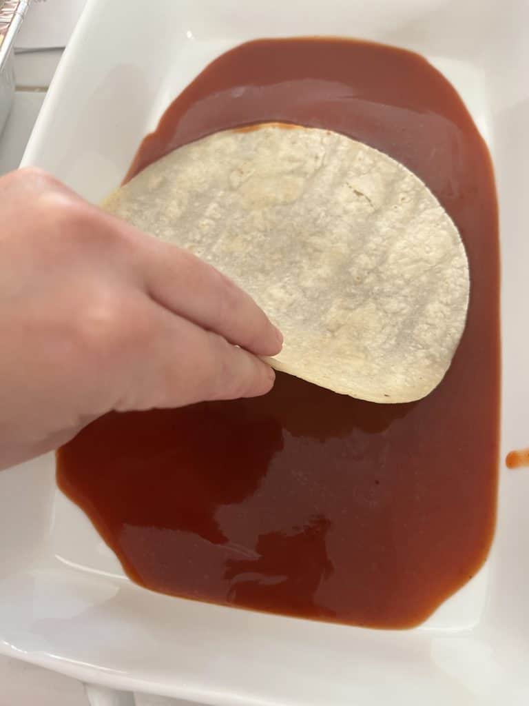 dipping the tortillas in sauce